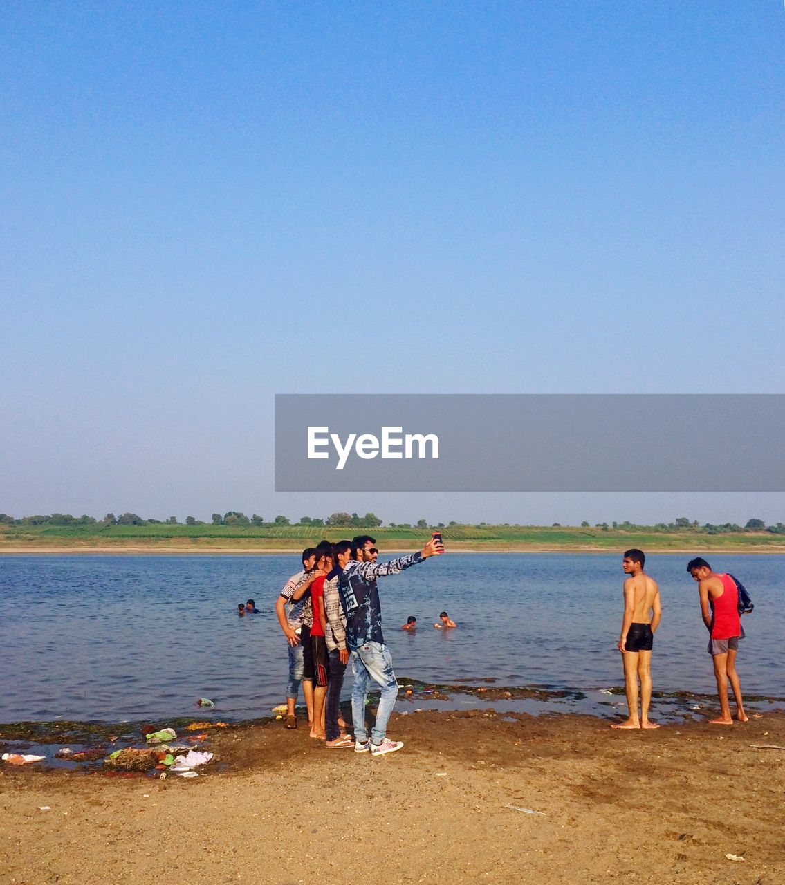 water, sky, group of people, beach, sea, shore, land, clear sky, nature, body of water, men, copy space, coast, day, adult, sunny, women, sand, blue, full length, leisure activity, holiday, outdoors, togetherness, lifestyles, trip, vacation, standing, group, travel, scenics - nature, occupation, beauty in nature, sunlight, horizon, sports, medium group of people