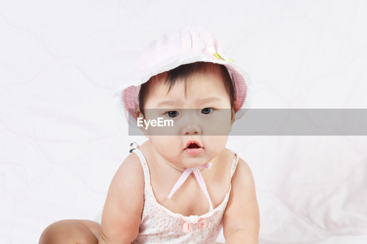 Cute baby girl sitting on bed at home