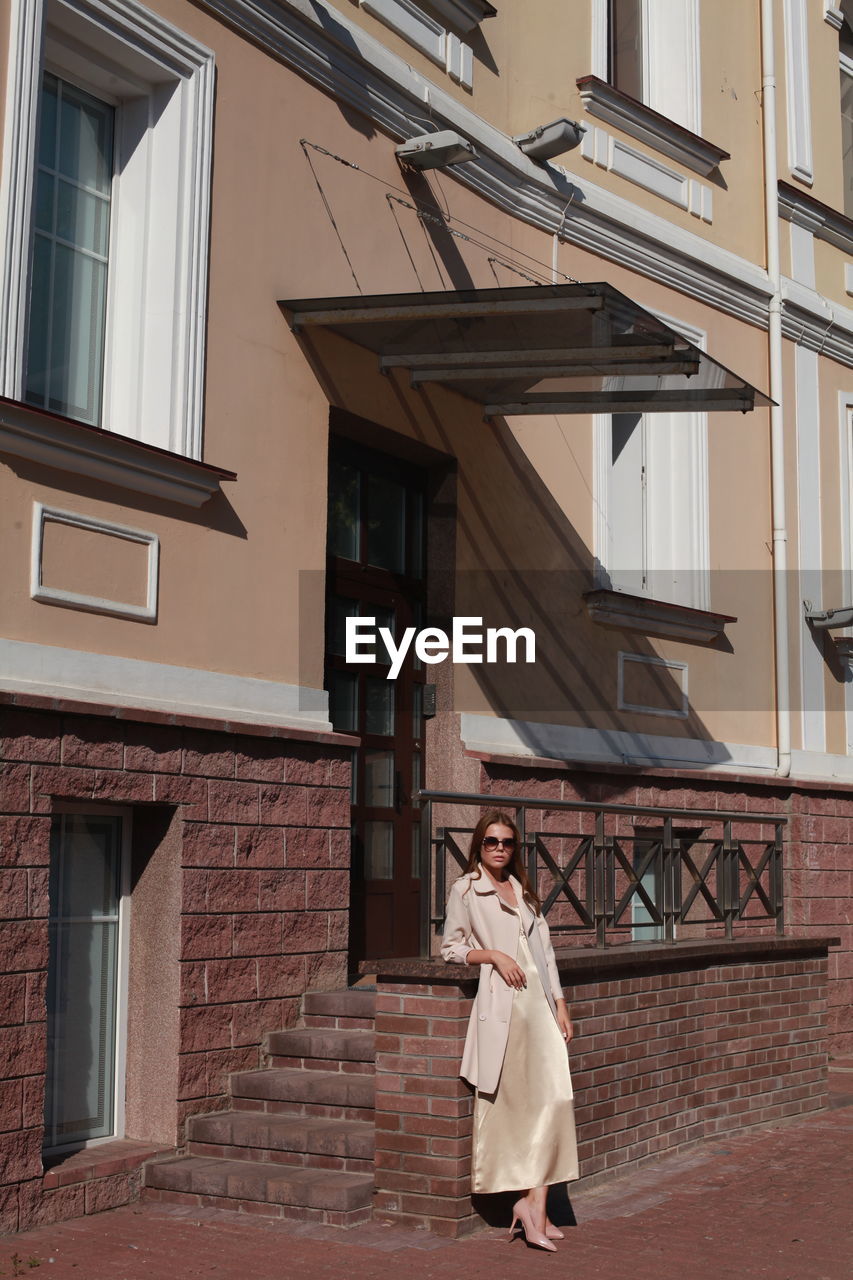 Young female model posing against building