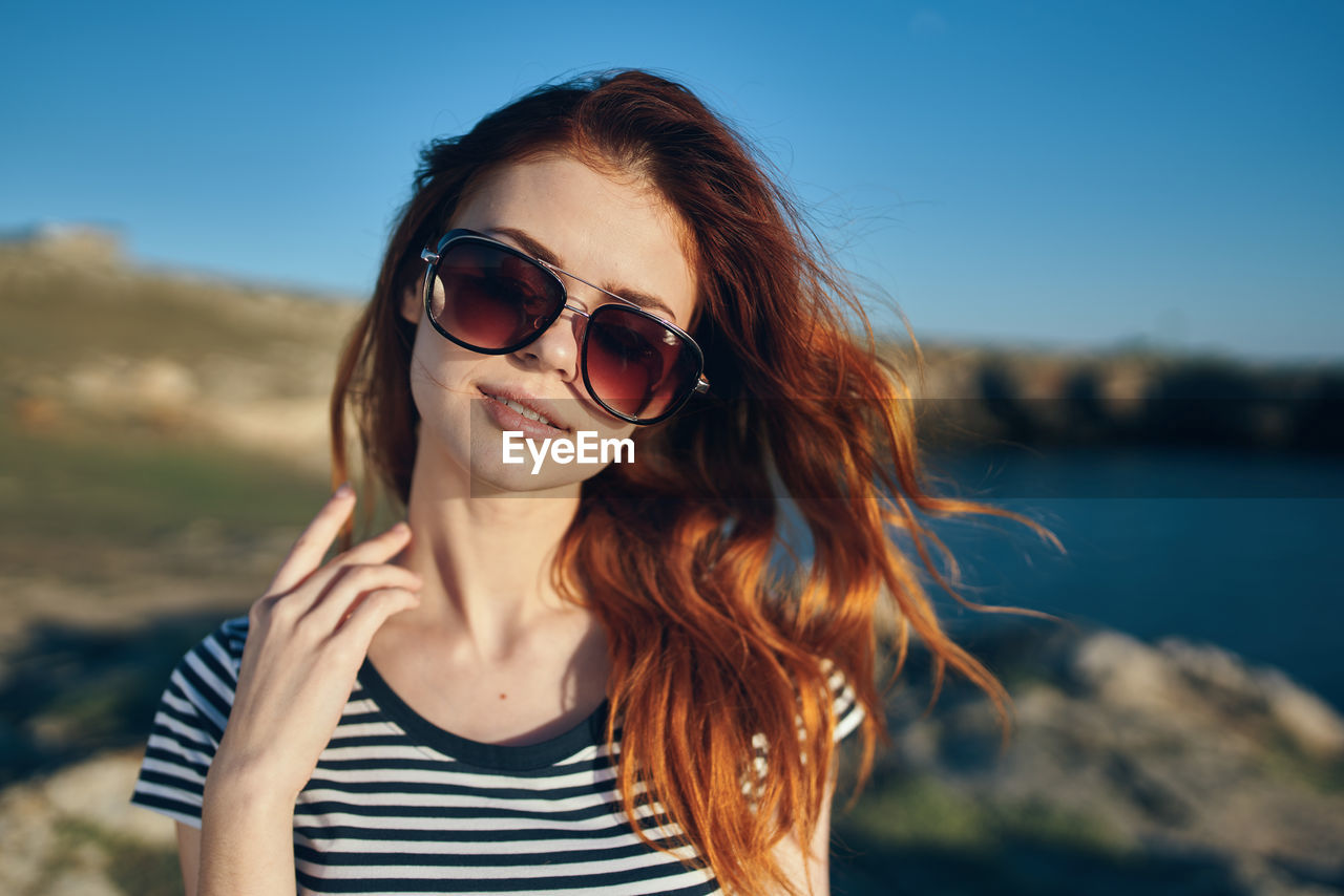 PORTRAIT OF BEAUTIFUL YOUNG WOMAN WEARING SUNGLASSES