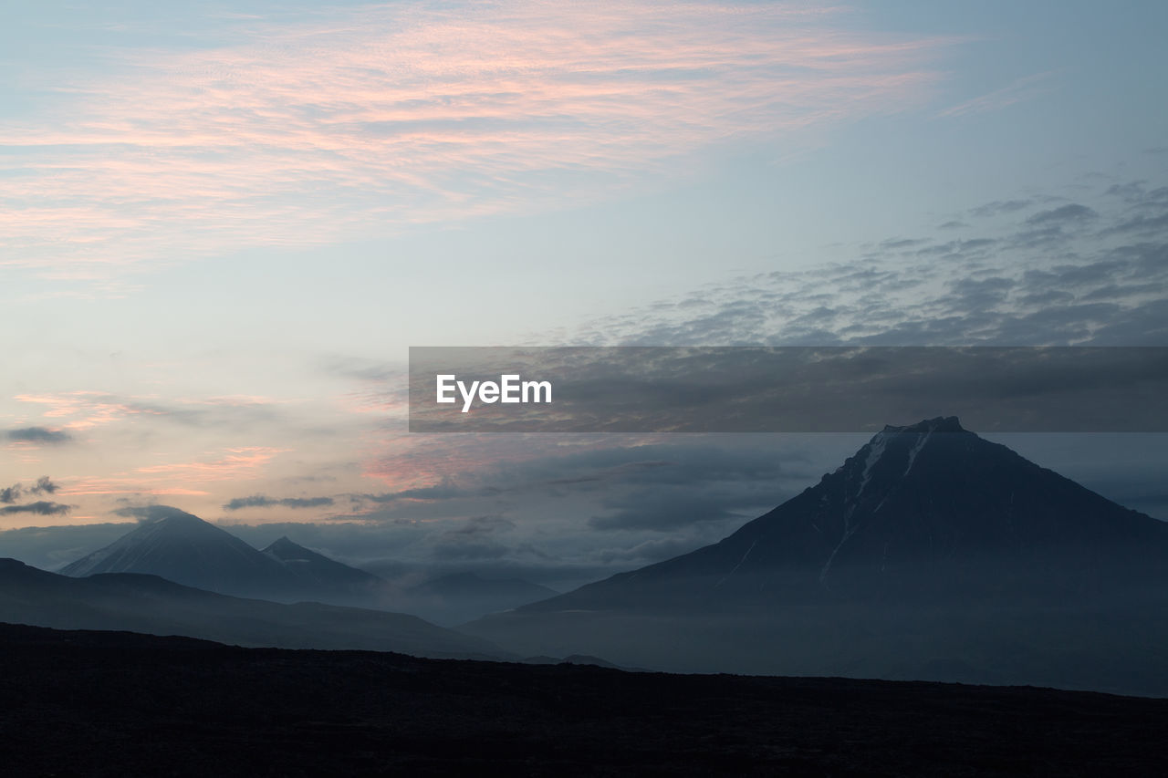 Scenic view of mountain against cloudy sky during sunset