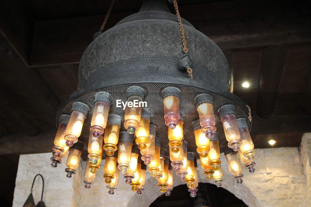 LOW ANGLE VIEW OF ILLUMINATED LIGHTING EQUIPMENT HANGING ON CEILING OF BUILDING