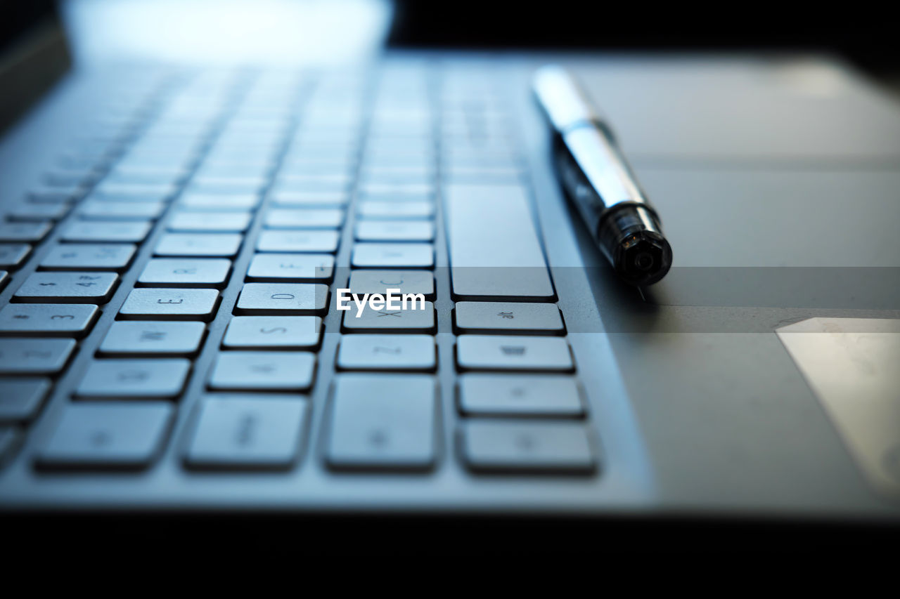 Laptop keyboard and pen - photo representing remote work concept with selective focus