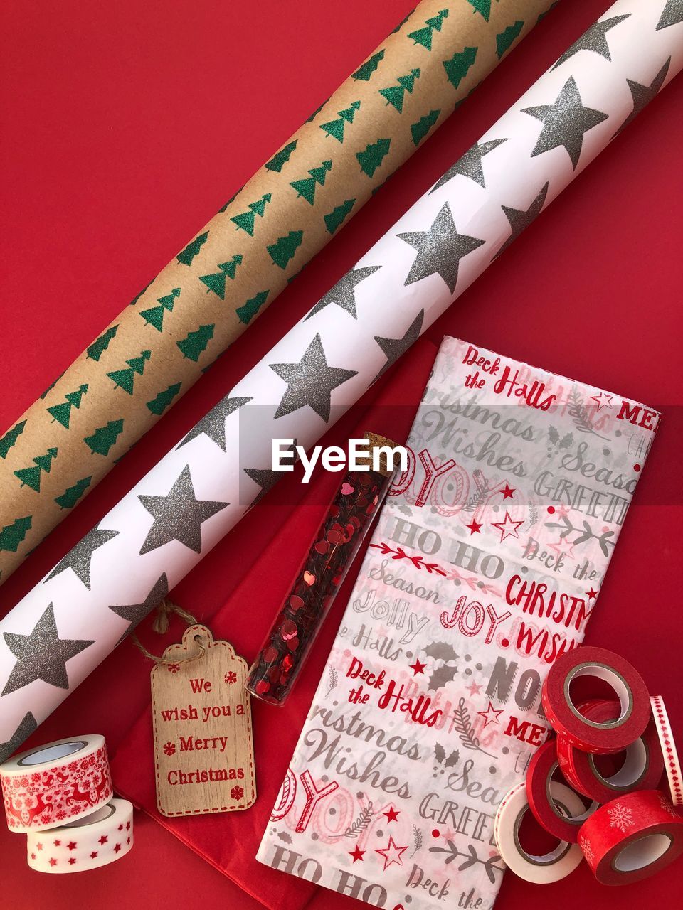 High angle view of wrapping papers and decorations over red background