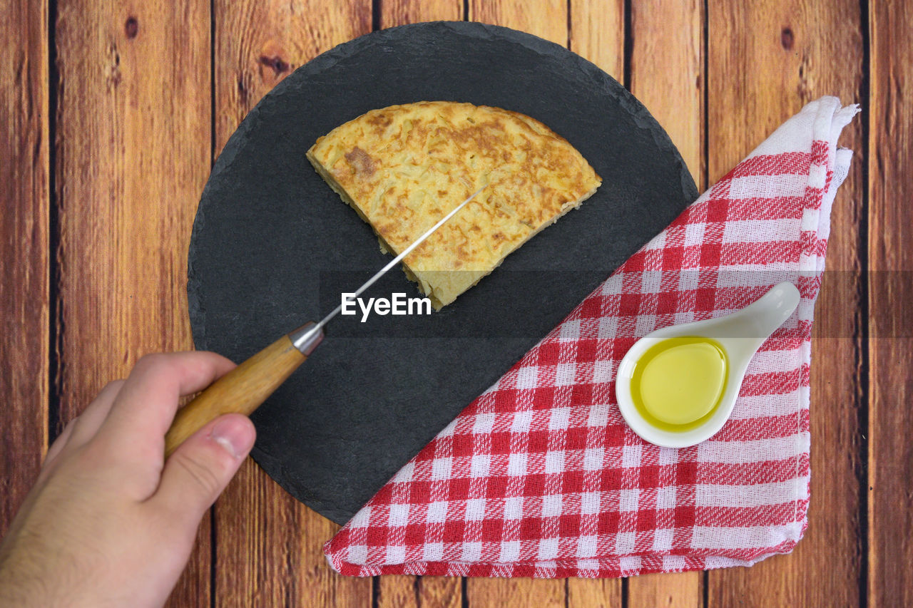 DIRECTLY ABOVE SHOT OF HAND HOLDING BREAD ON TABLE