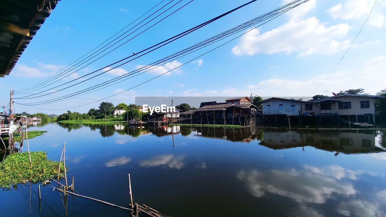 reflection, water, architecture, sky, built structure, nature, building exterior, cloud, cable, building, city, transportation, travel destinations, blue, no people, cityscape, lake, residential district, outdoors, house, electricity, travel, tree, environment, landscape, day, vehicle, tranquility, nautical vessel, beauty in nature, mode of transportation, technology, tourism, business finance and industry