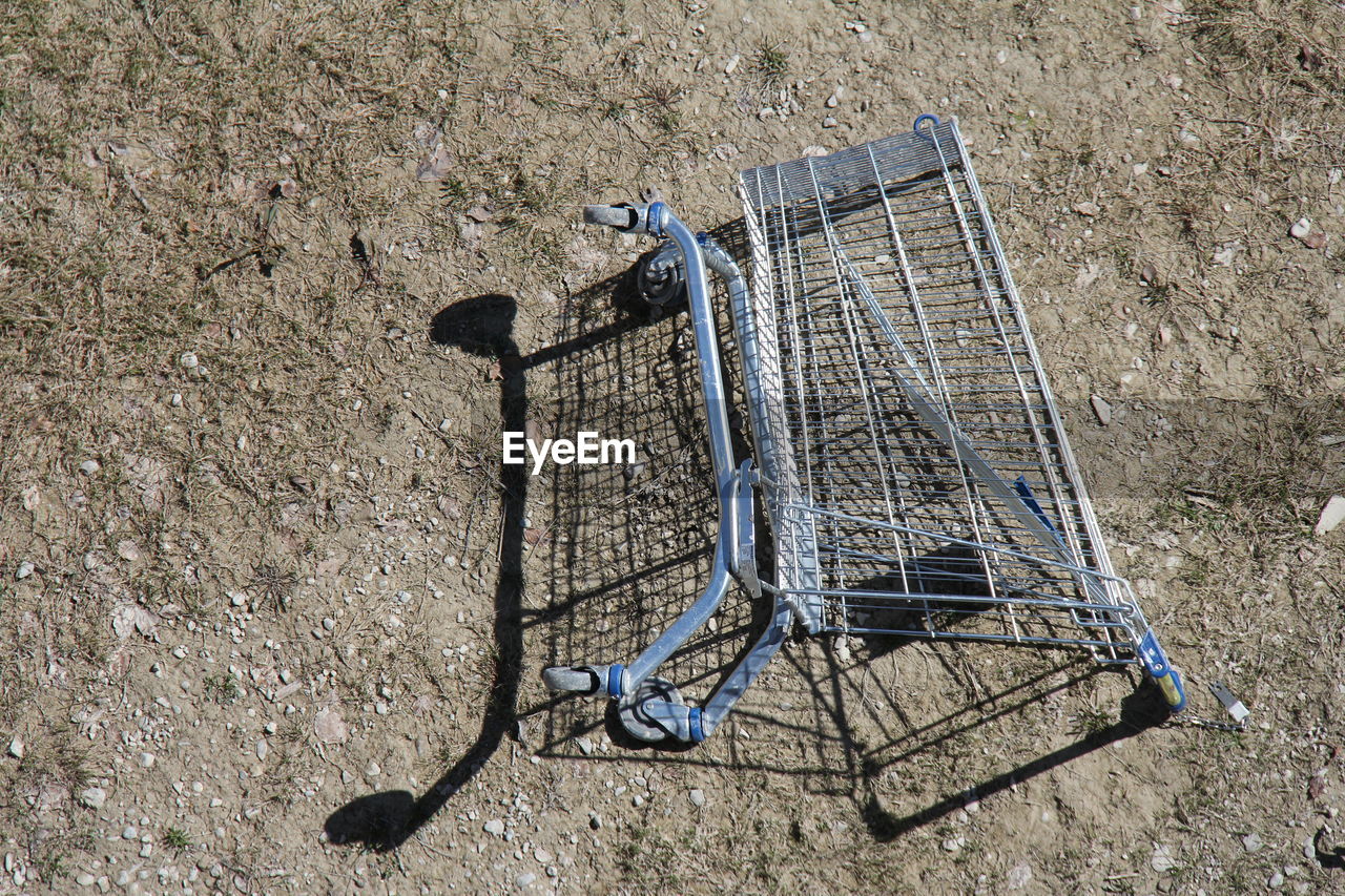 shopping cart, high angle view, no people, day, metal, shadow, shopping, iron, vehicle, absence, nature, trolley, abandoned, outdoors, sunlight, consumerism, cart, land, empty