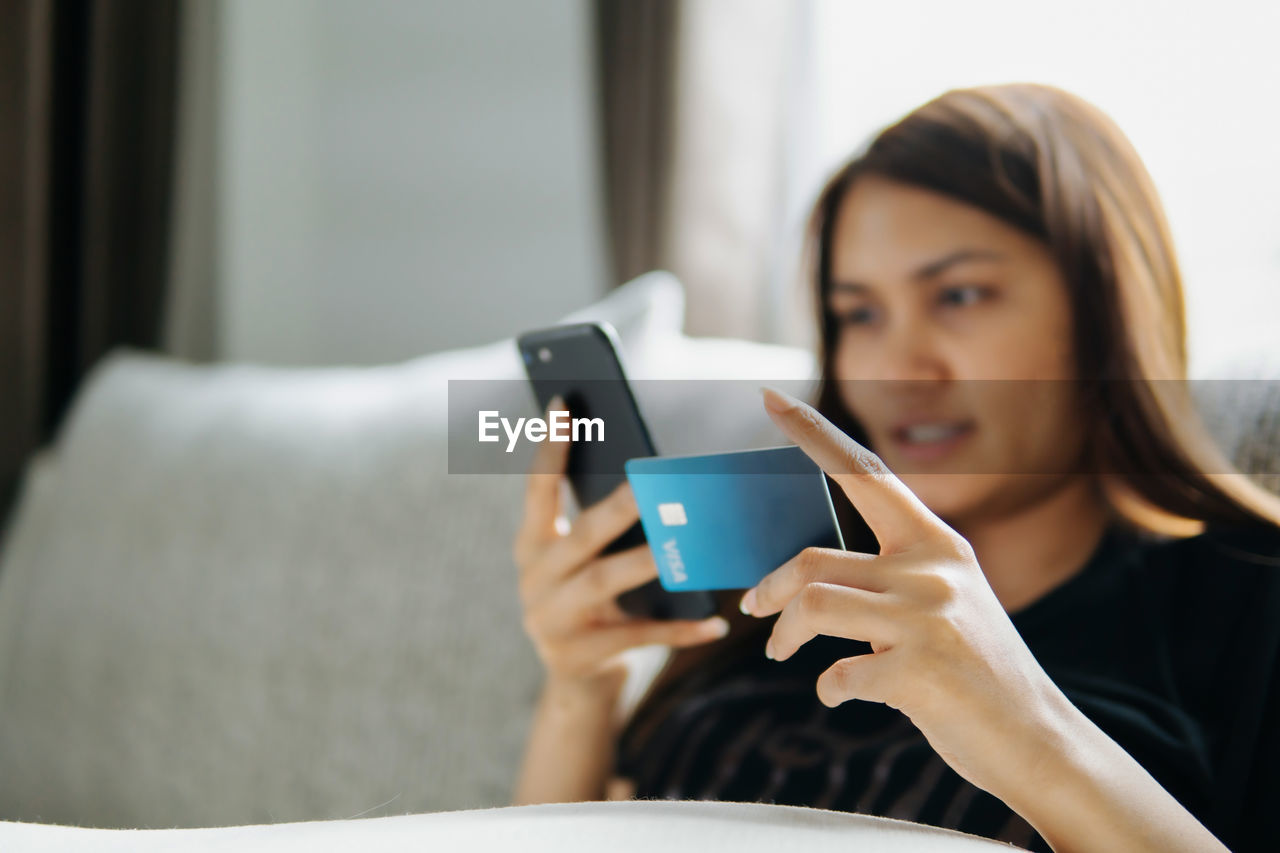 MIDSECTION OF WOMAN USING MOBILE PHONE IN CUP
