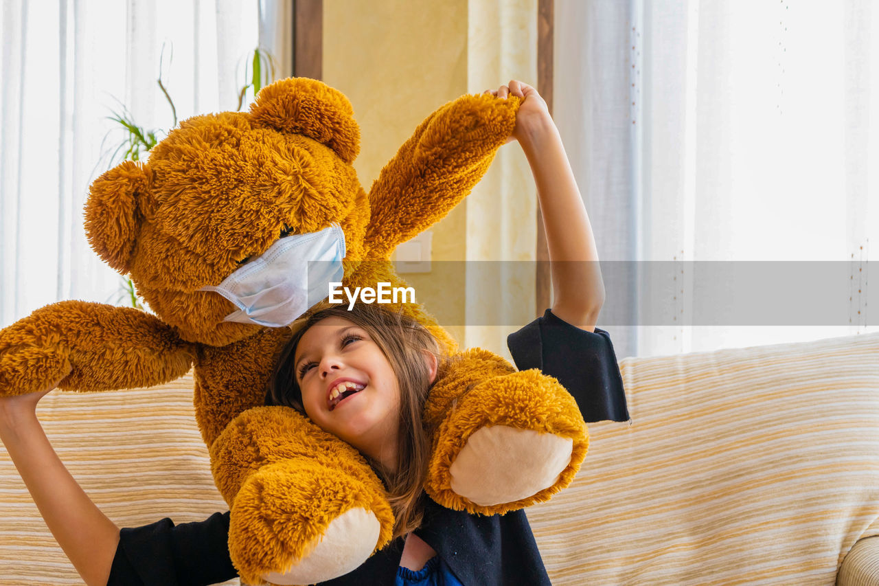 Smiling girl playing with teddy bear