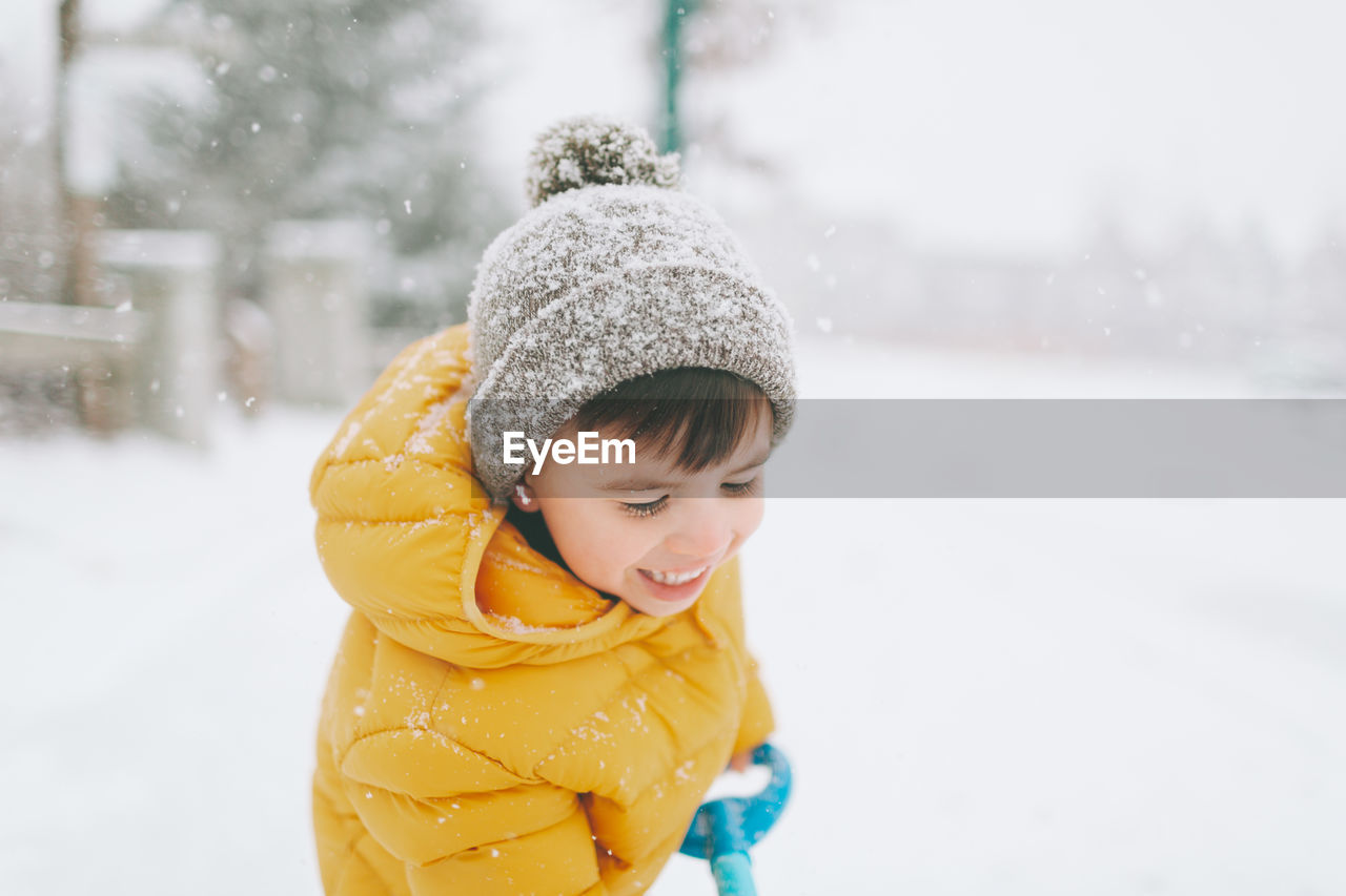 Smiling boy cleaning snow