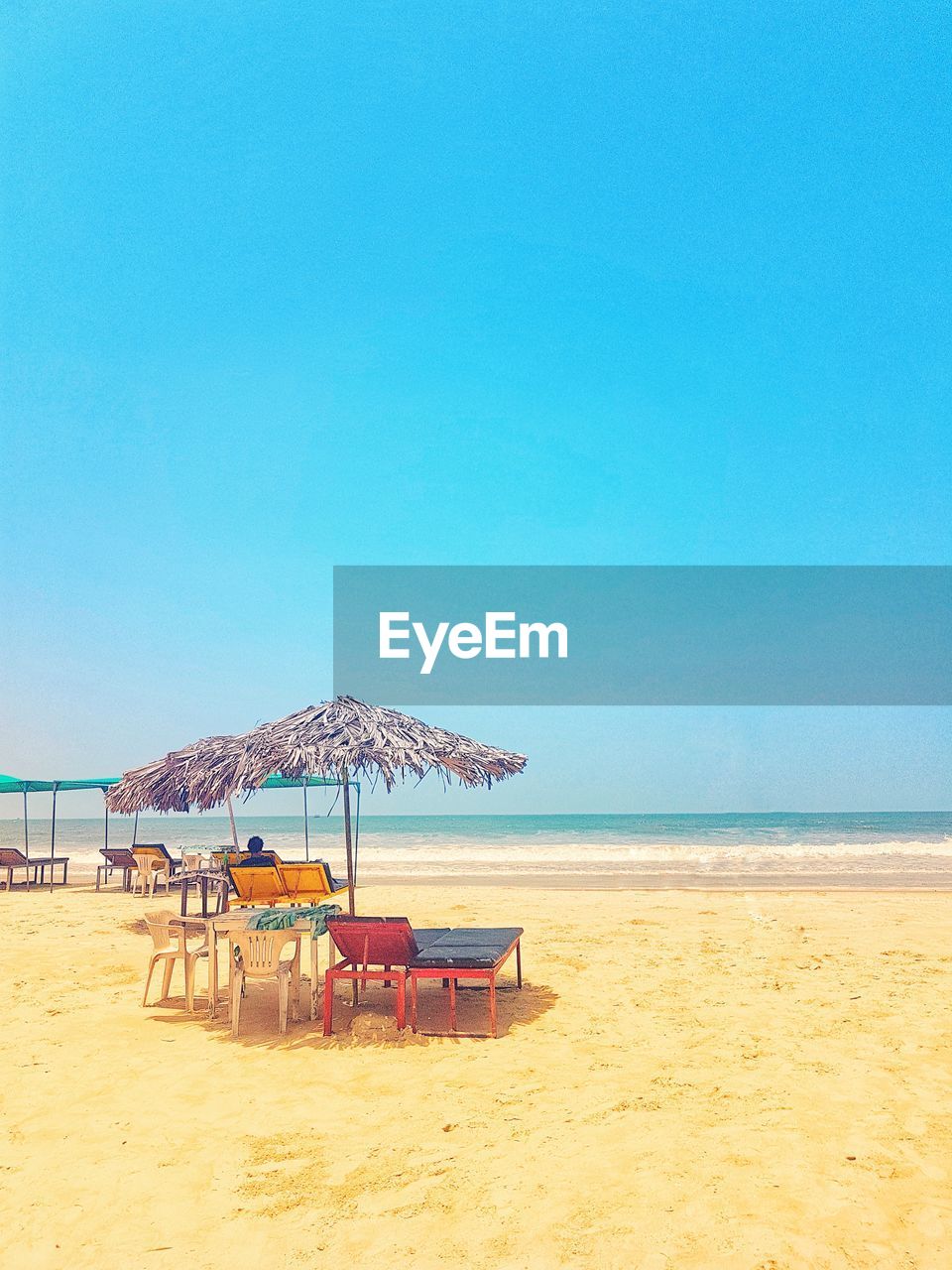 Deck chairs on beach against clear blue sky