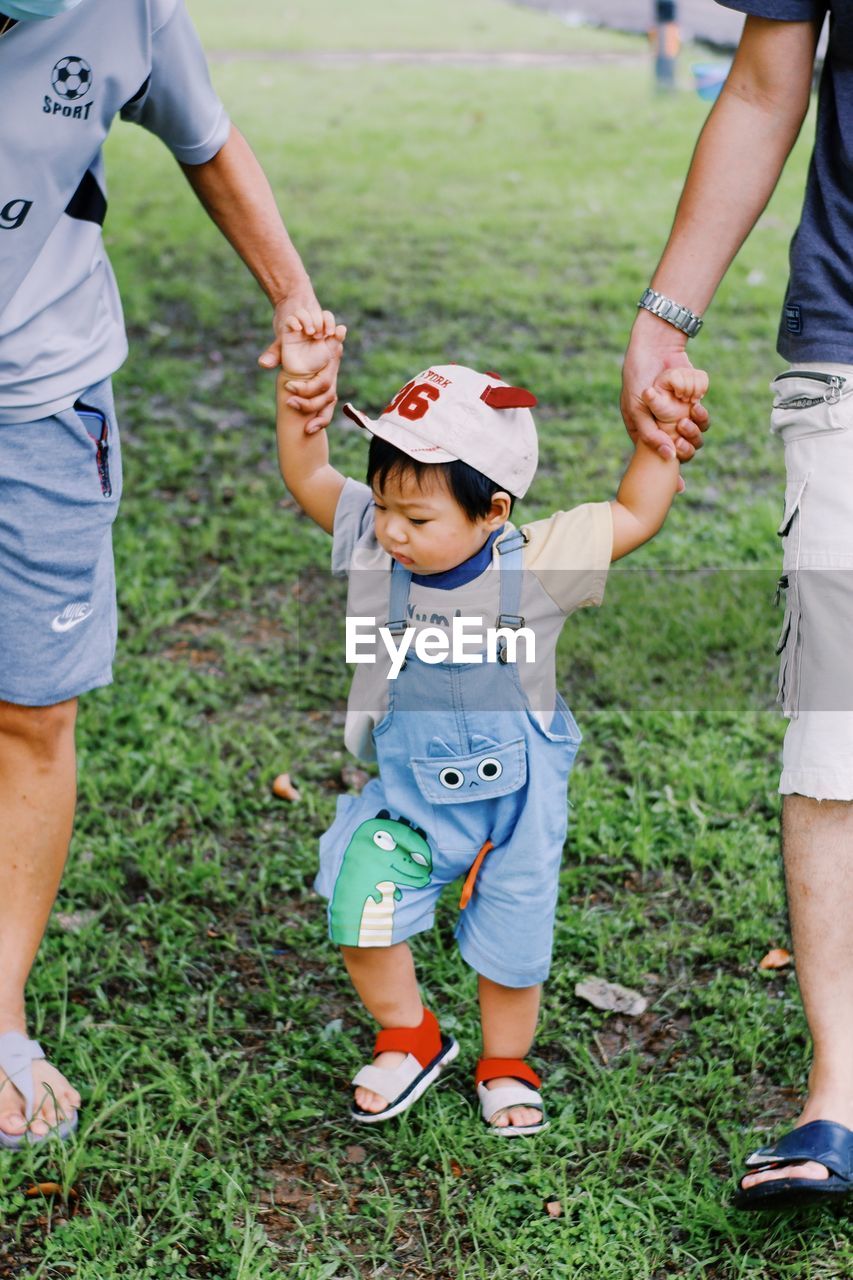 Boy holding hands walking in park