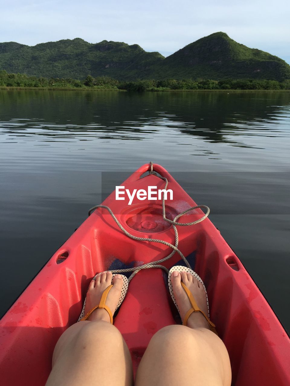 Low section of woman sitting on boat in lake against mountains