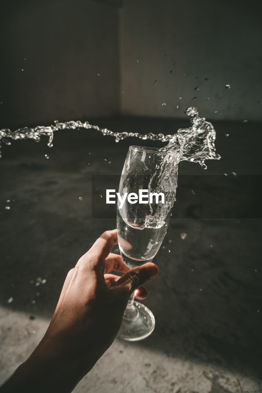 MAN HOLDING GLASS OF WATER SPLASHING