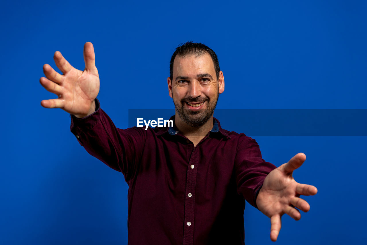 PORTRAIT OF SMILING MAN AGAINST BLUE BACKGROUND