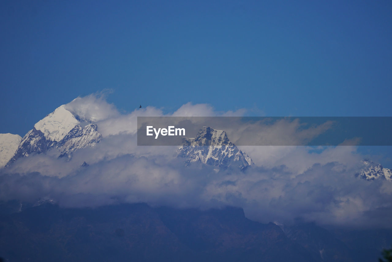 Low angle view of snowcapped mountains against blue sky