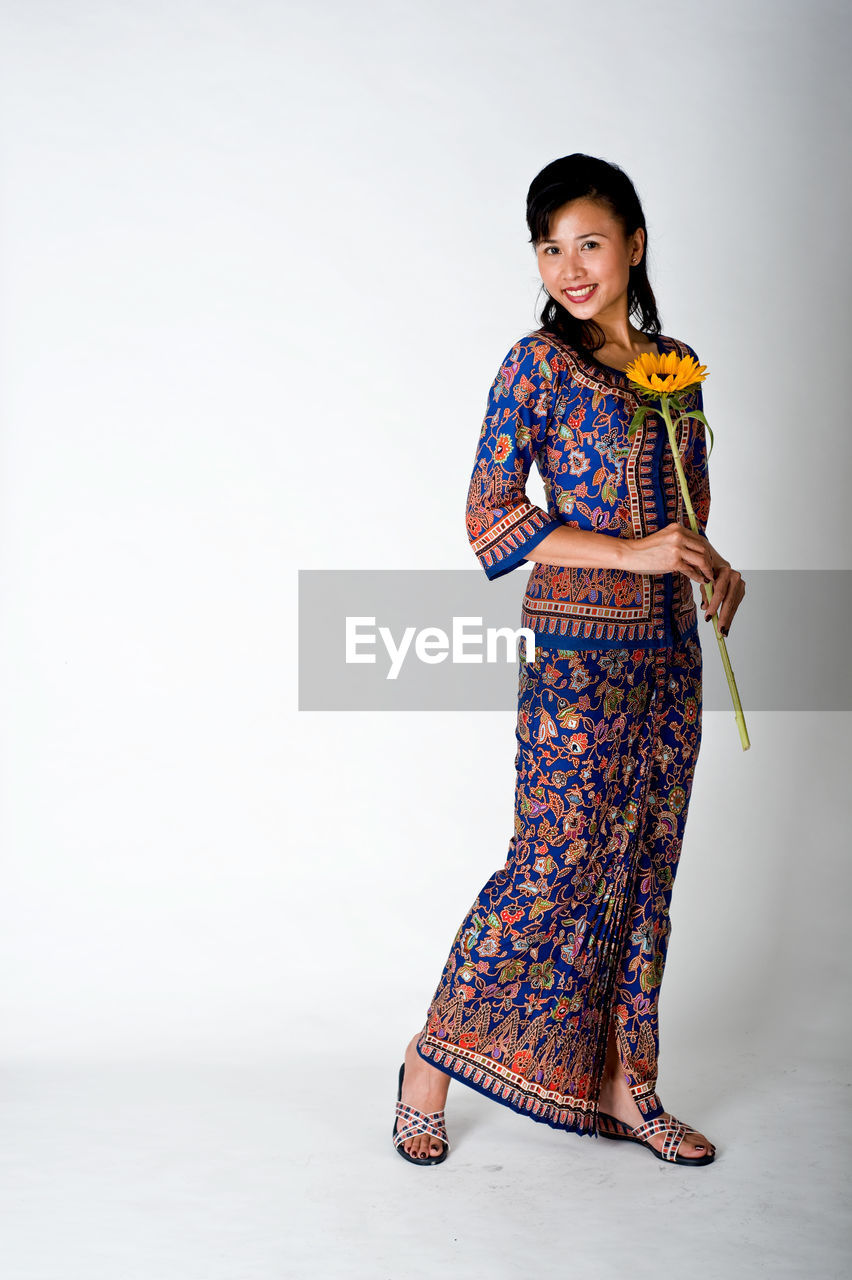 Portrait of smiling woman in traditional clothing standing against white background