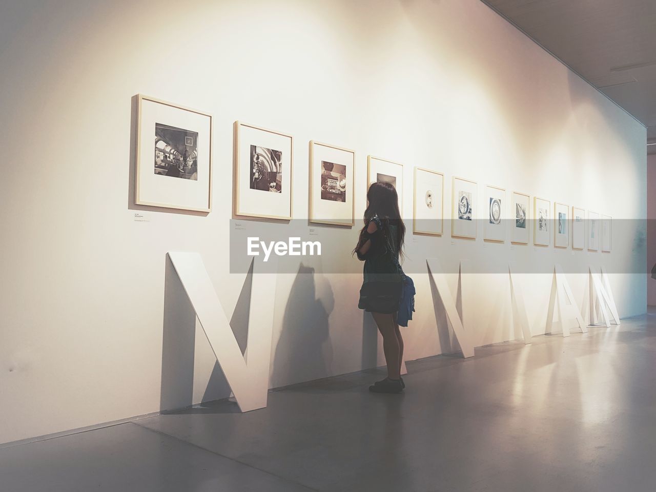 FULL LENGTH OF WOMAN STANDING AGAINST WALL IN MUSEUM