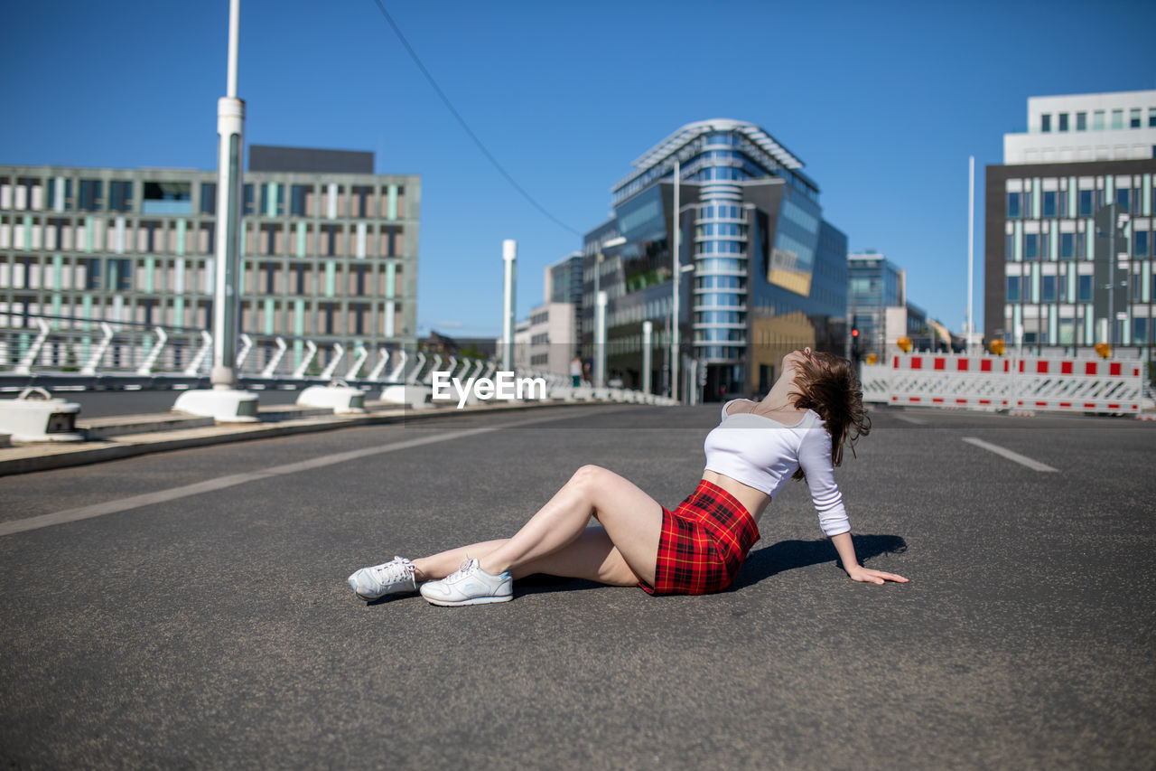 Young woman on road against sky in city