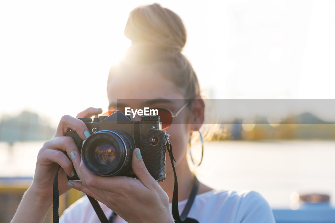 Close-up of woman photographing against clear sky