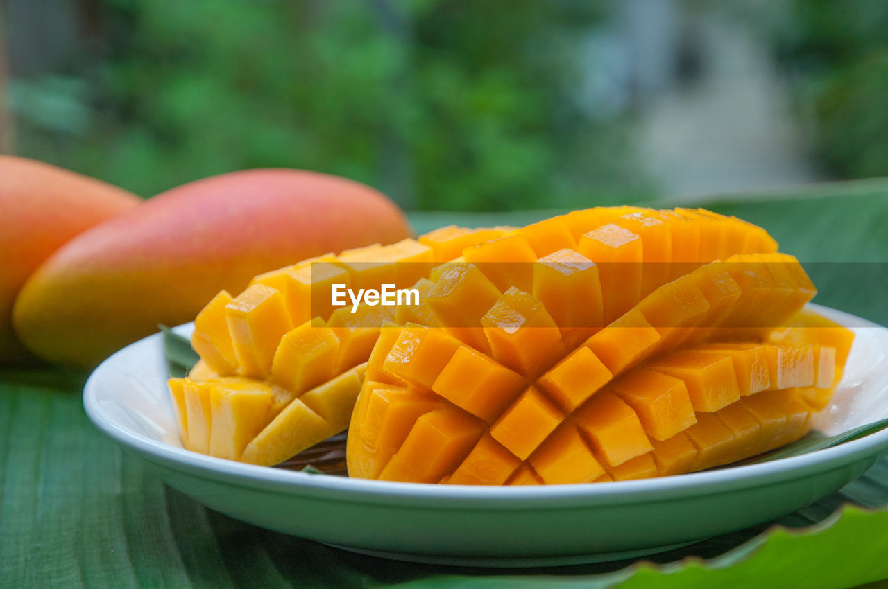 Close-up of sliced mangoes in plate on banana leaf