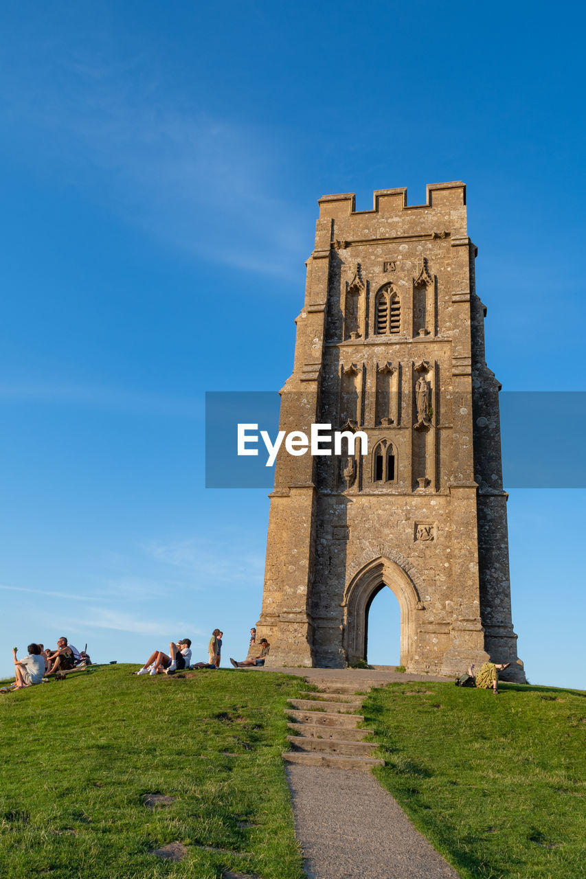 Landscape photo of tourists sitting on the summit at glastonbury tor in somerset