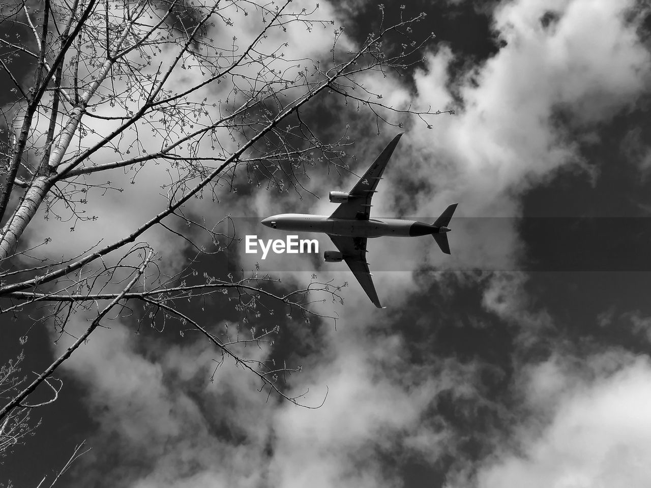 low angle view of airplane flying against cloudy sky