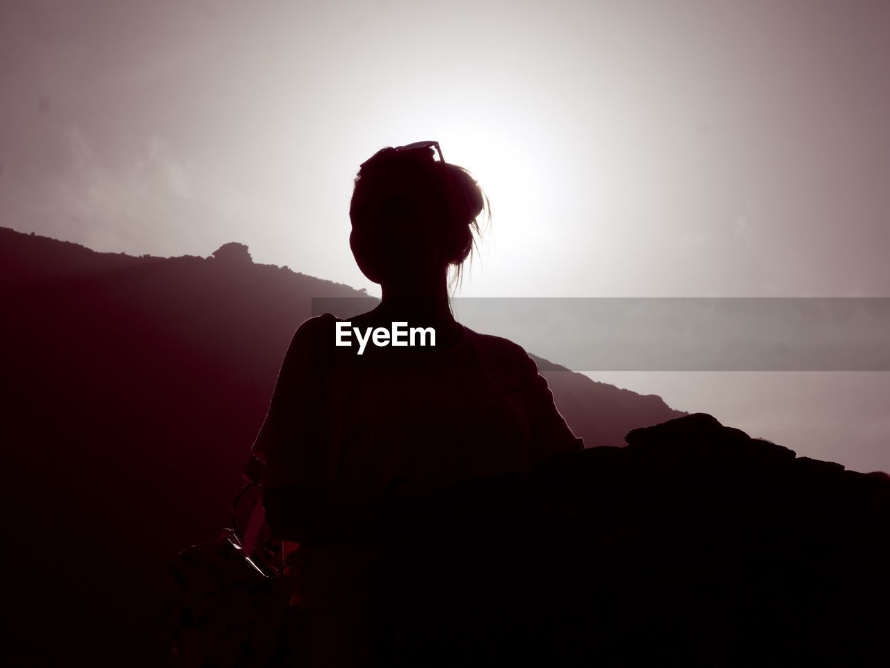 Low angle view of silhouette woman standing on mountain against sky