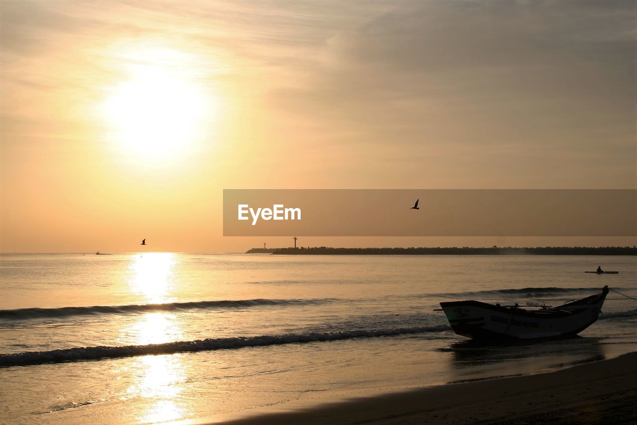 Boat moored in sea against sky during sunset