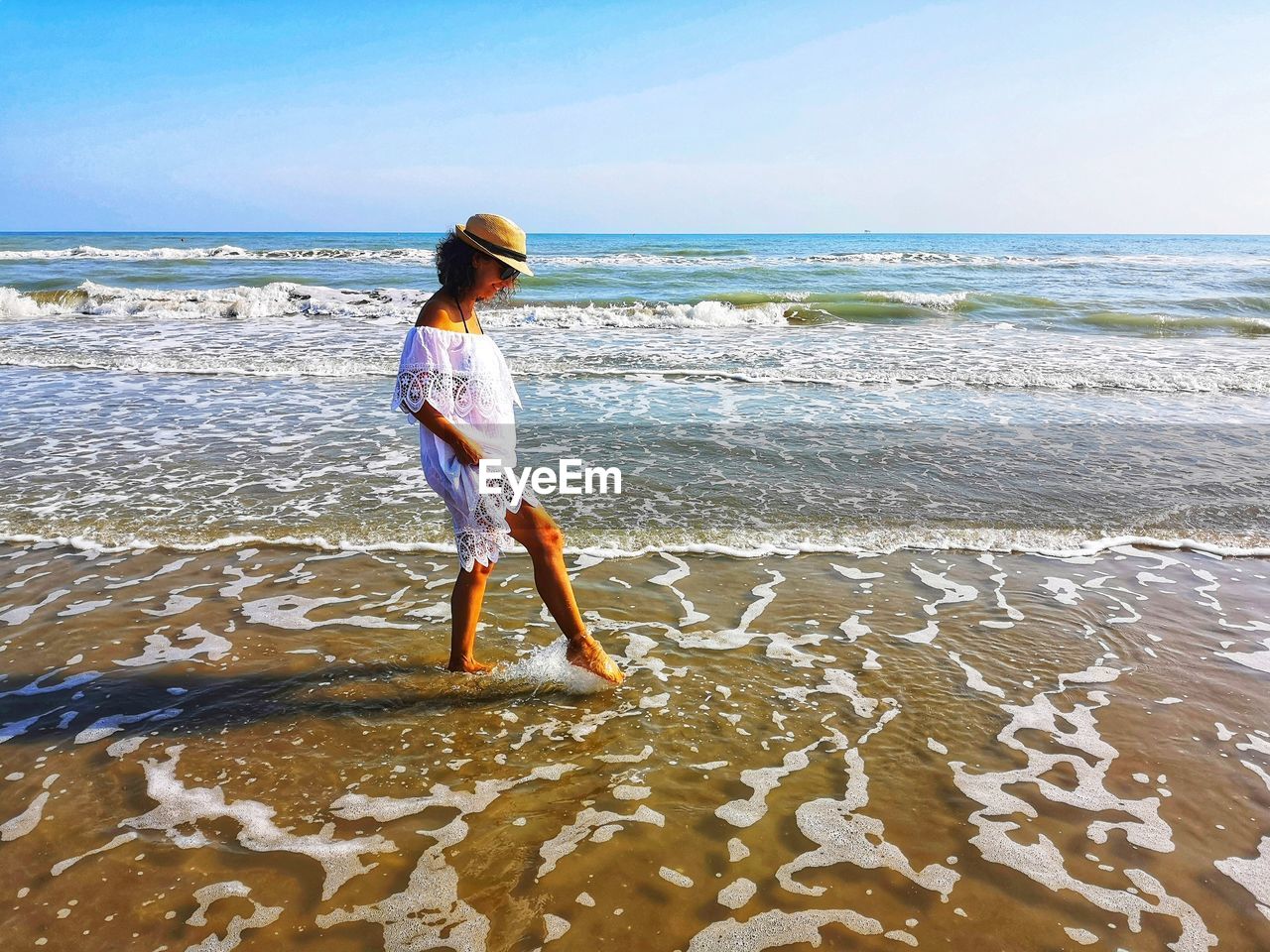 REAR VIEW OF BOY STANDING ON BEACH AGAINST SEA