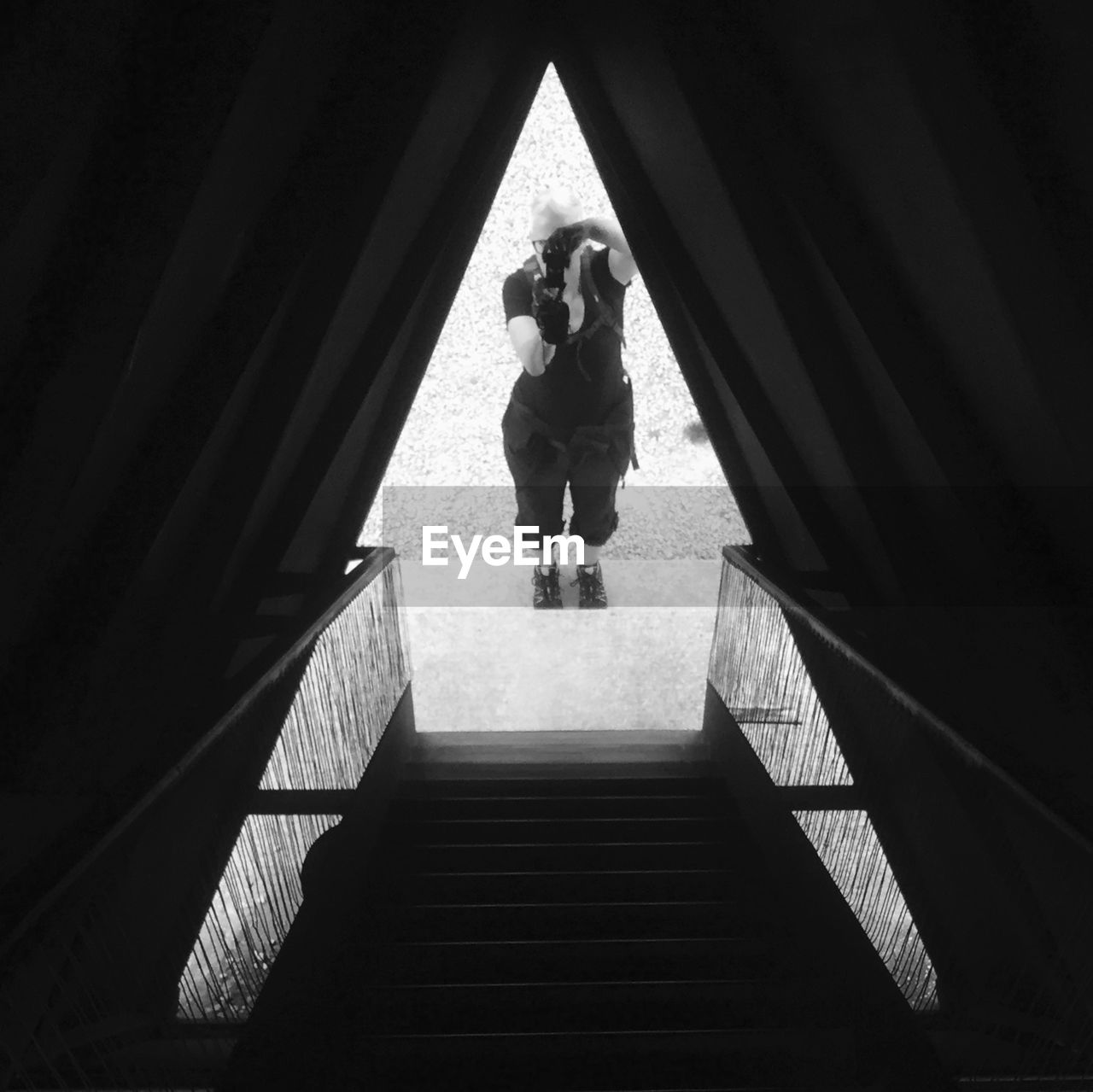 LOW ANGLE VIEW OF WOMAN STANDING ON RAILING