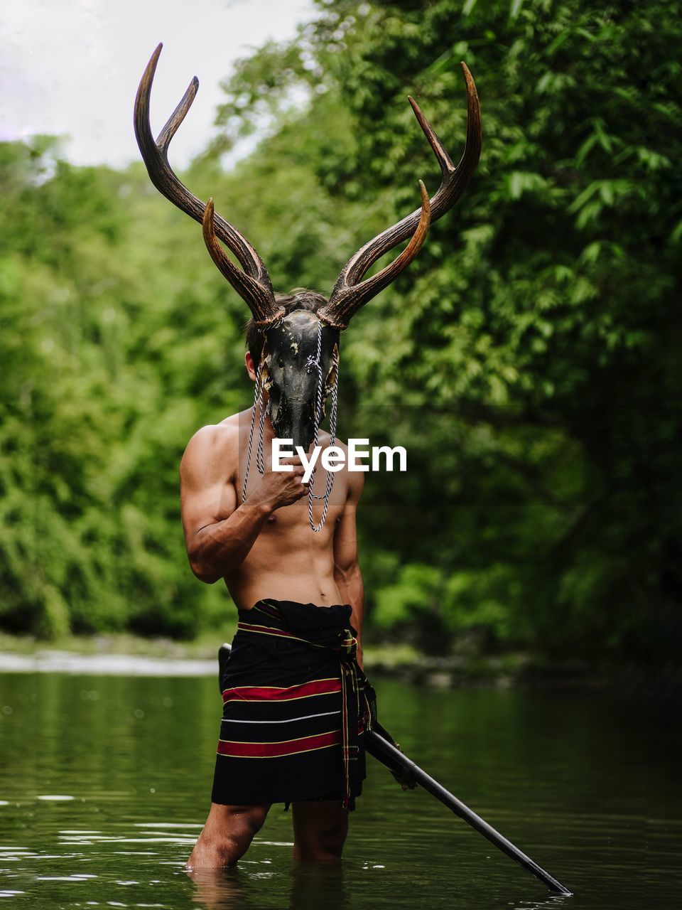 Full length of shirtless man standing in lake