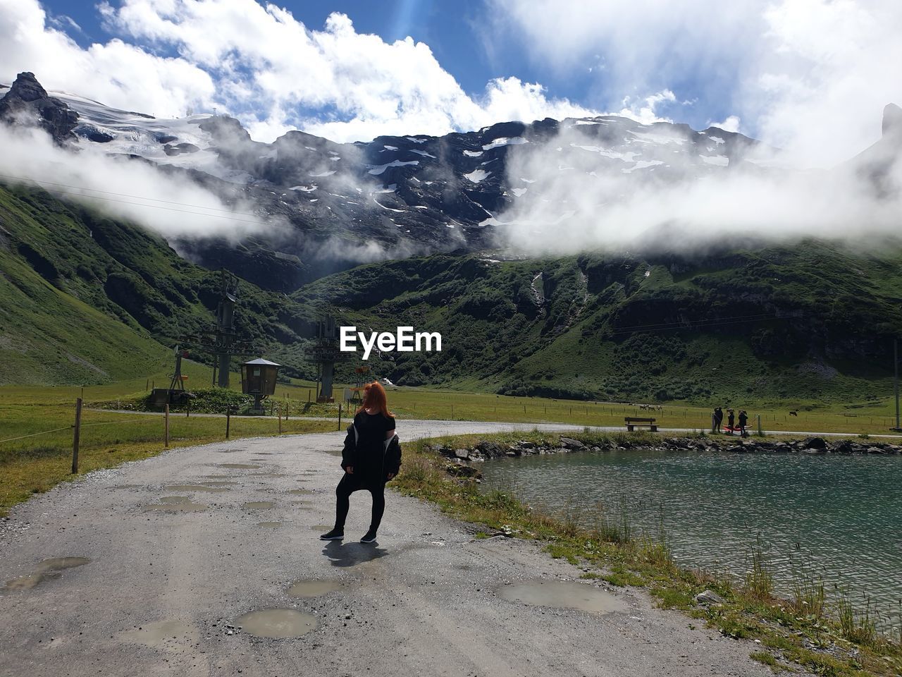 Woman standing on road leading towards mountains 