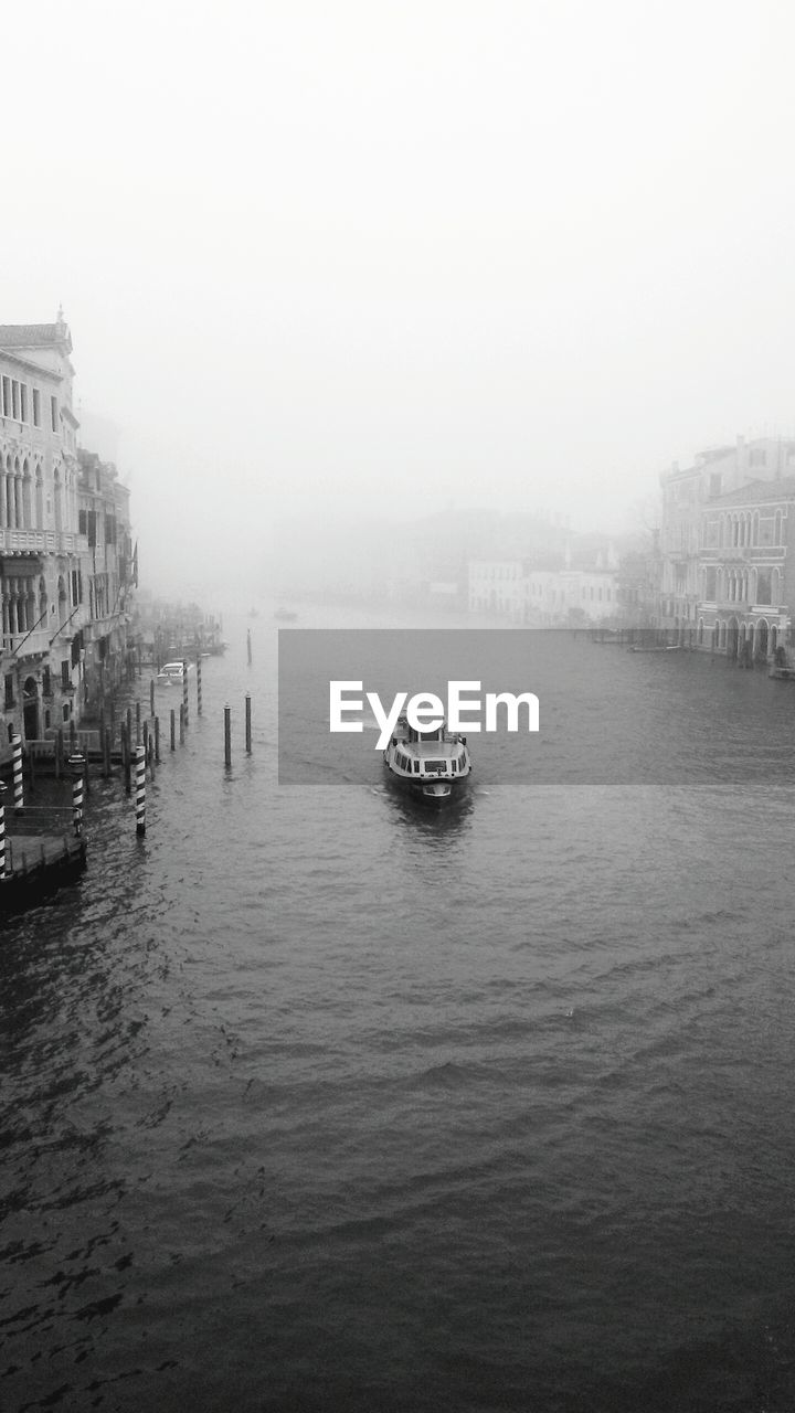 High angle view of boat sailing on river in city against clear sky