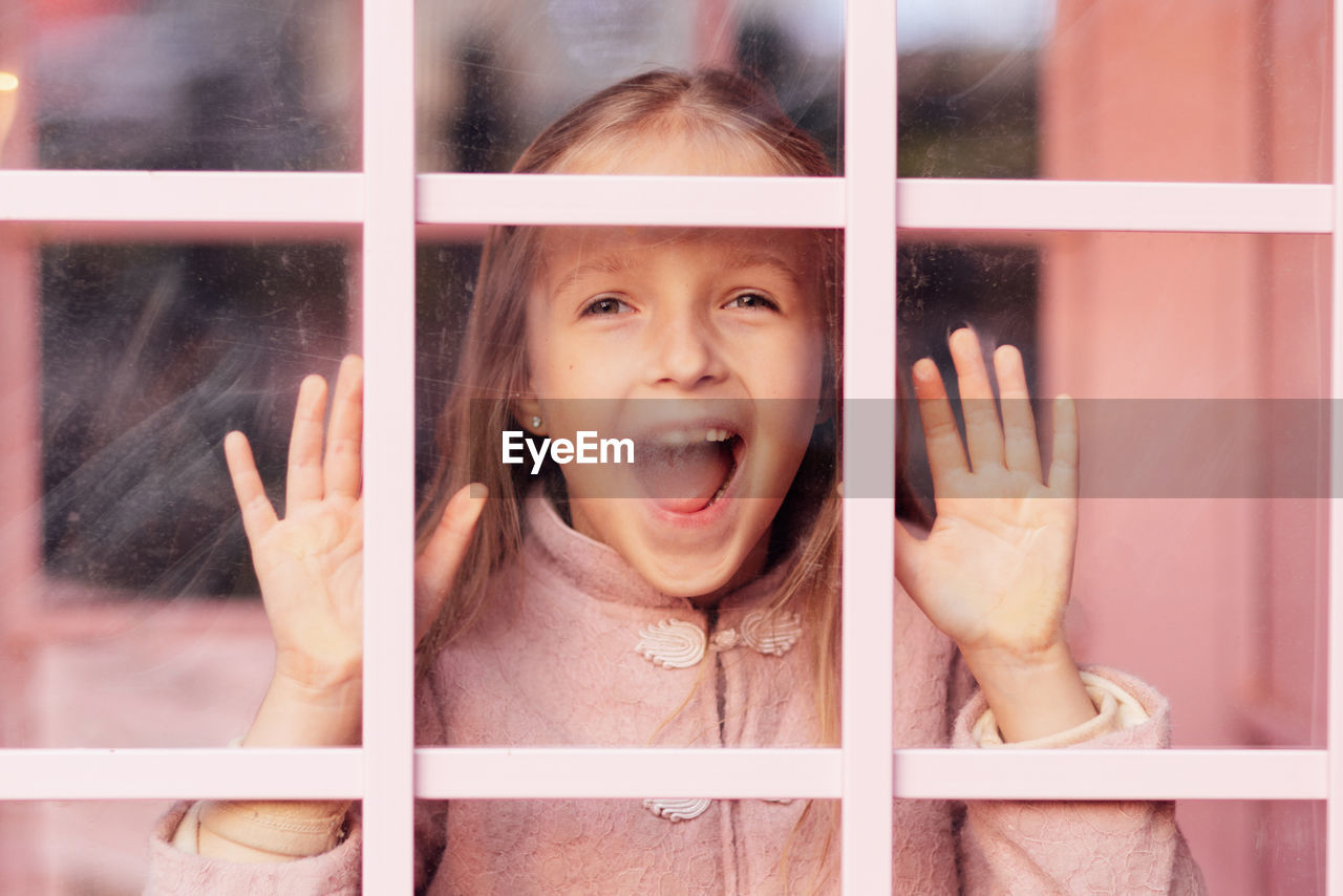 portrait of smiling young woman looking through window