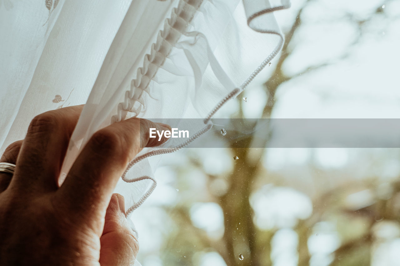 Close-up of human hand holding curtain