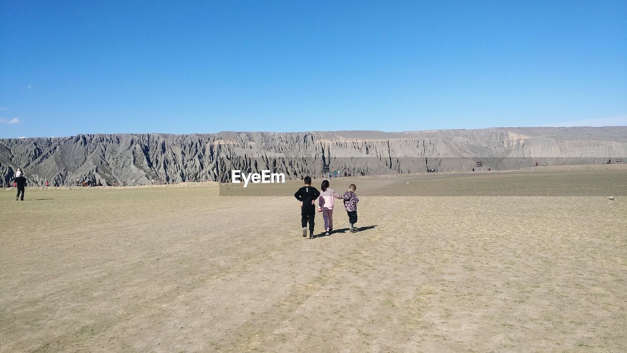 REAR VIEW OF PEOPLE WALKING ON LAND