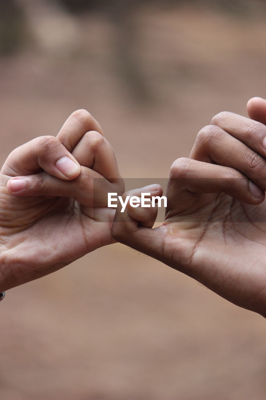 Close-up of man and woman giving pinkie promise