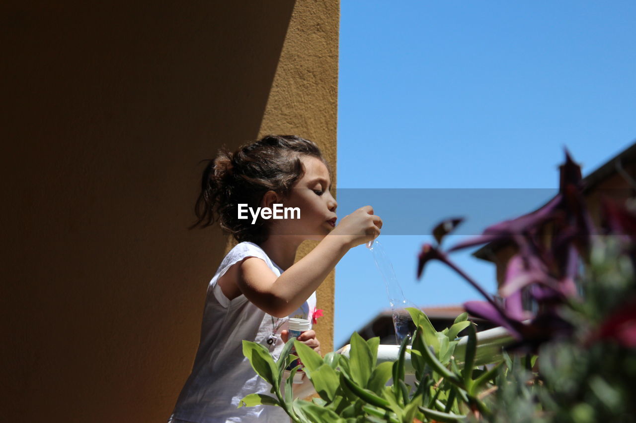 Portrait of girl looking up against clear sky