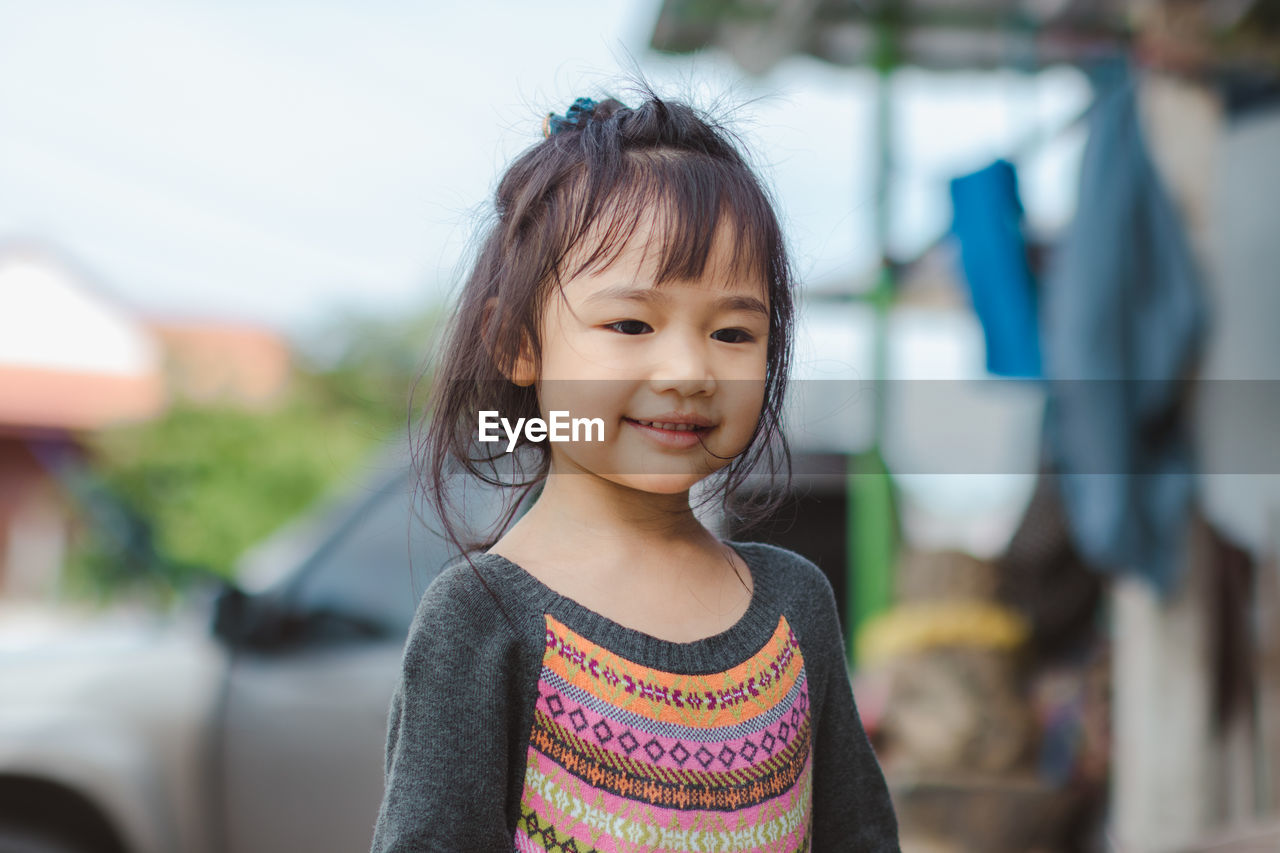 Cute smiling girl looking away while standing outdoors