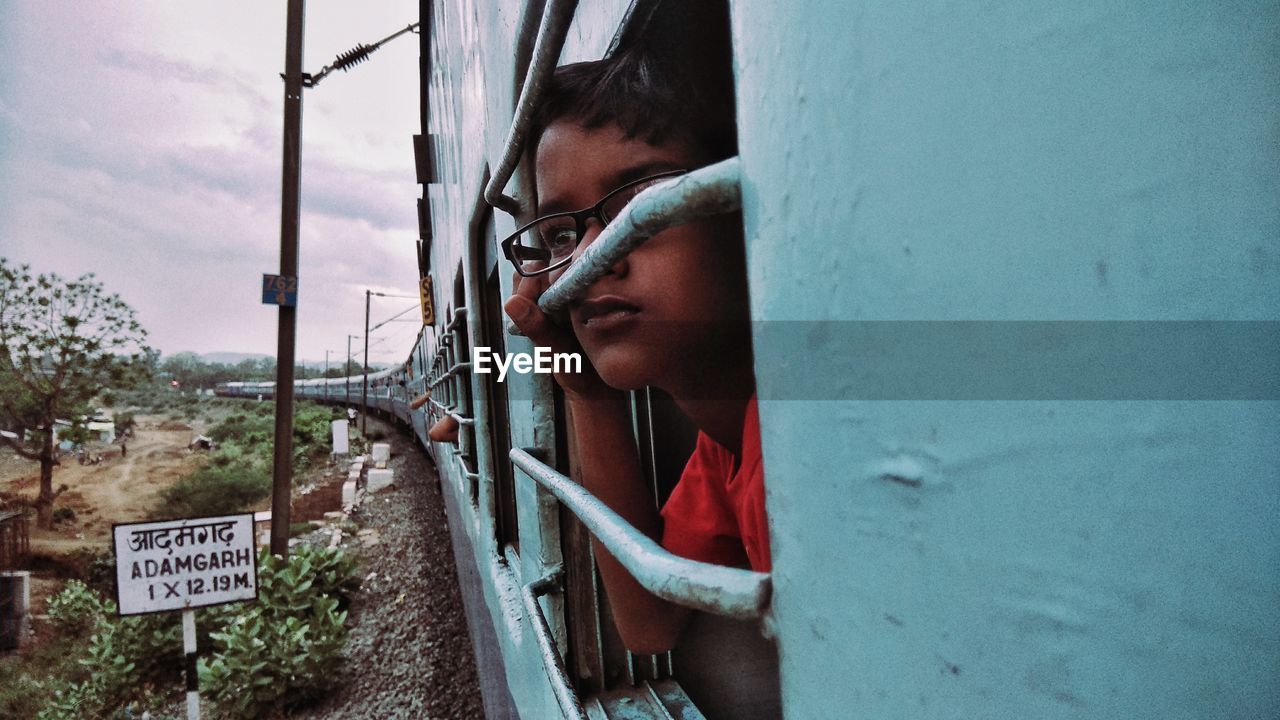 Close-up of boy looking through train window