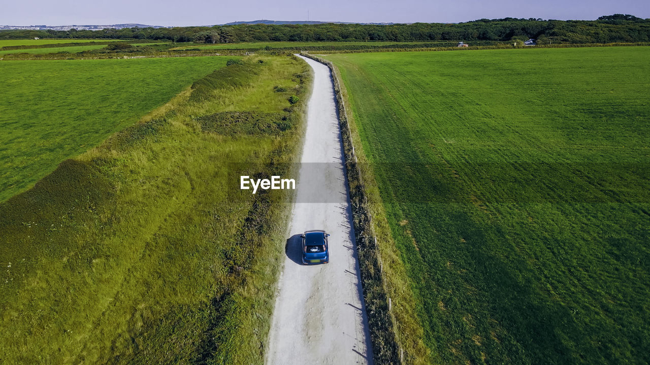 The car is moving on a sandy country road