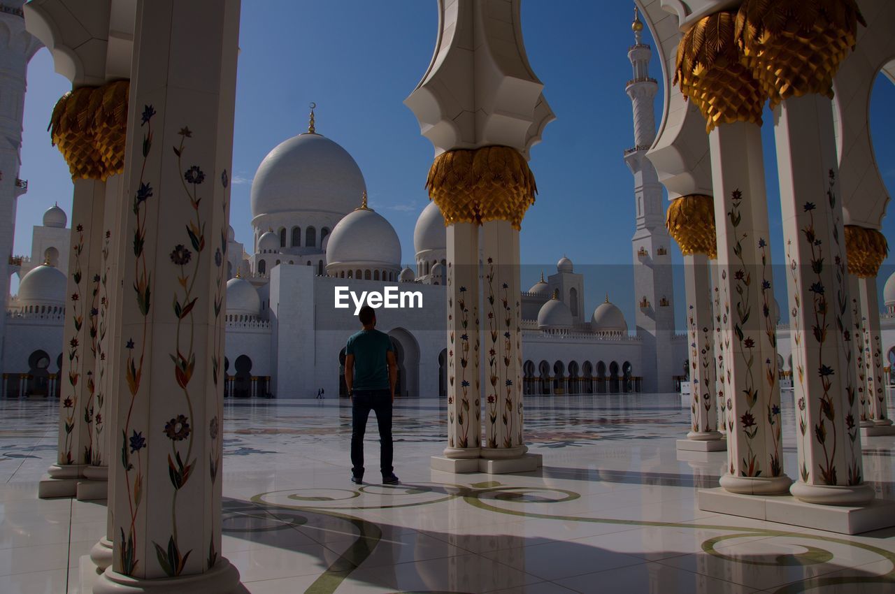 Rear view of man standing by columns at sheikh zayed mosque