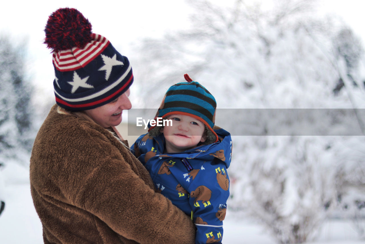 Boy wearing hat against trees during winter