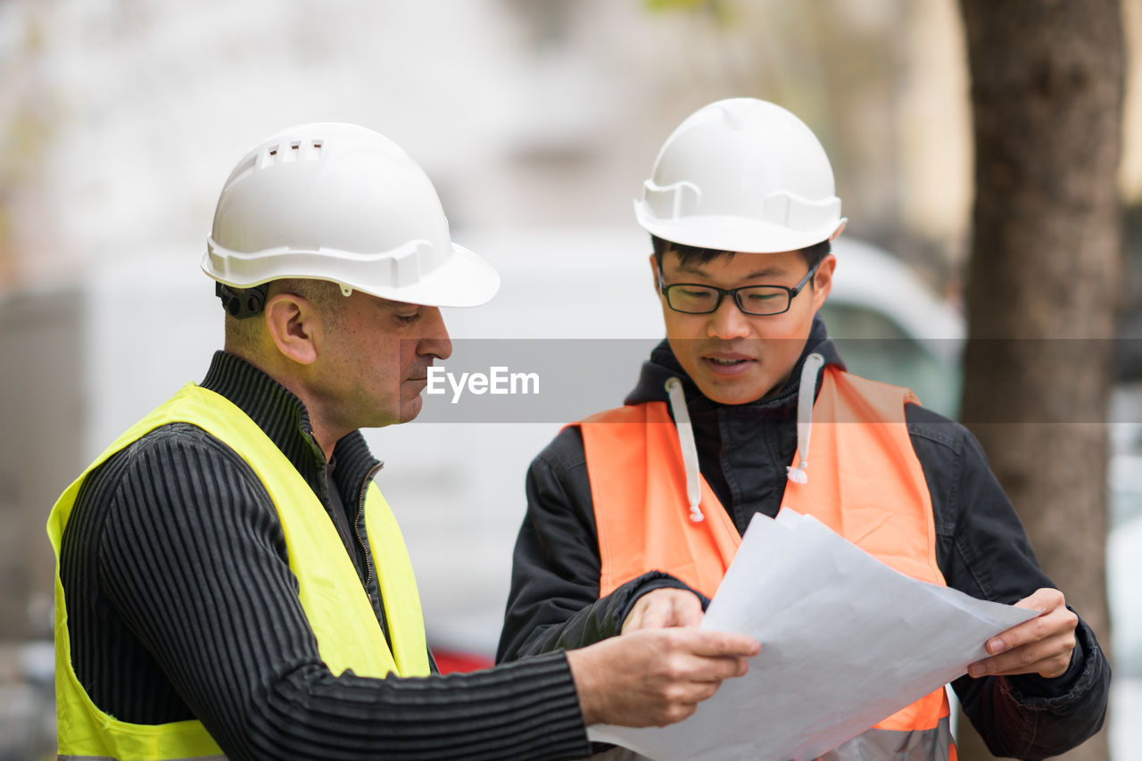 Engineers discussing while standing at construction site