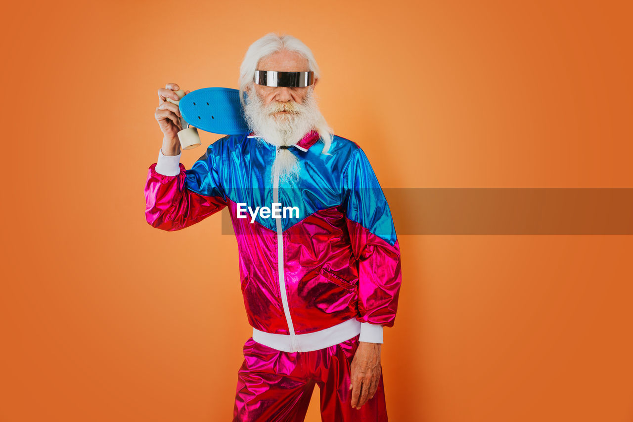 FULL LENGTH PORTRAIT OF MAN STANDING AGAINST ORANGE BACKGROUND