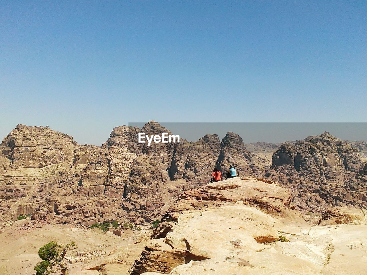 Rear view of people sitting on rock formation at petra