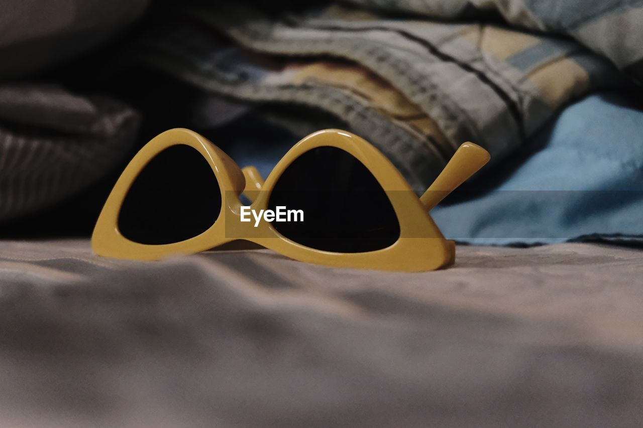 Close-up of sunglasses on bed
