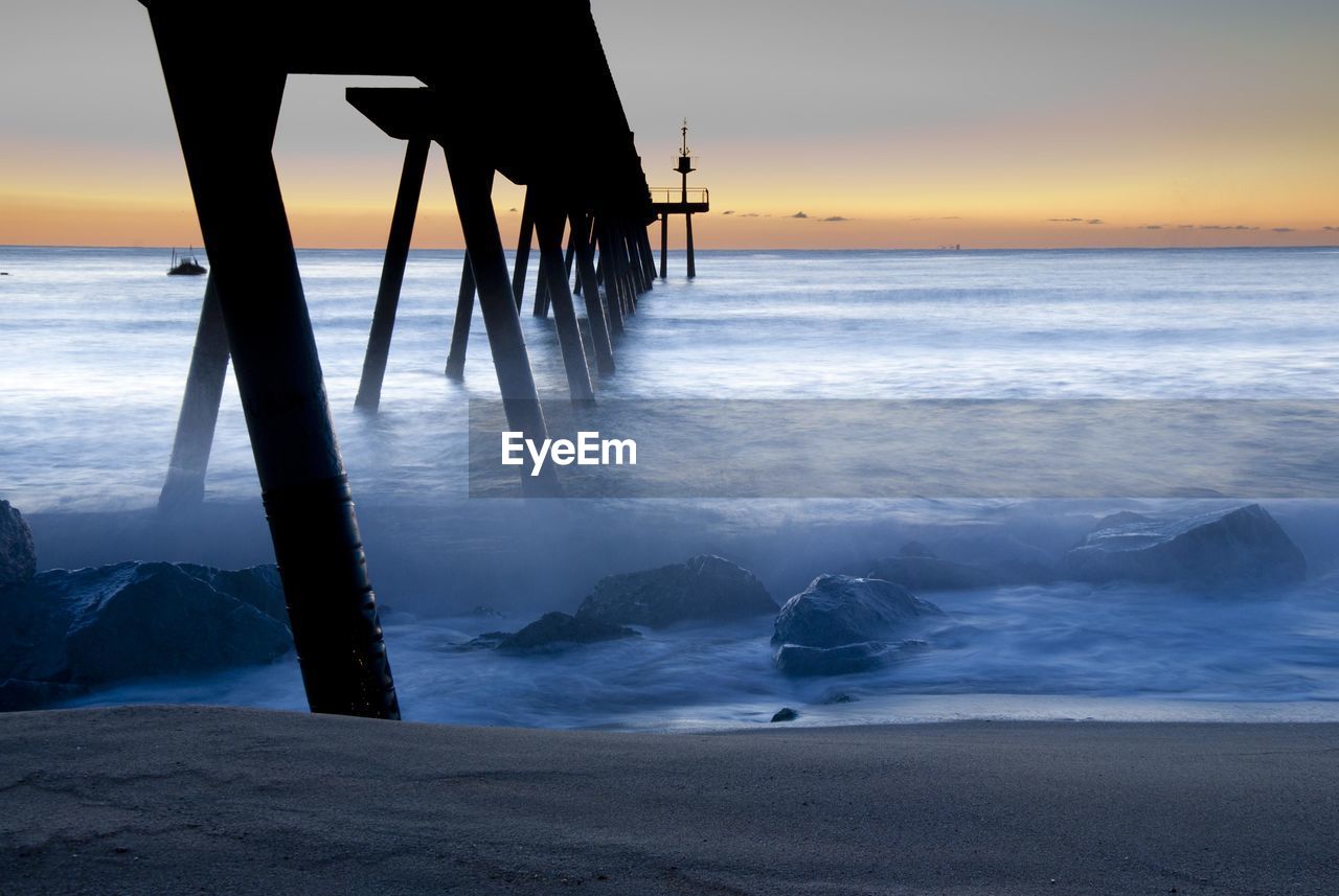 Silhouette of pier on sea during sunset