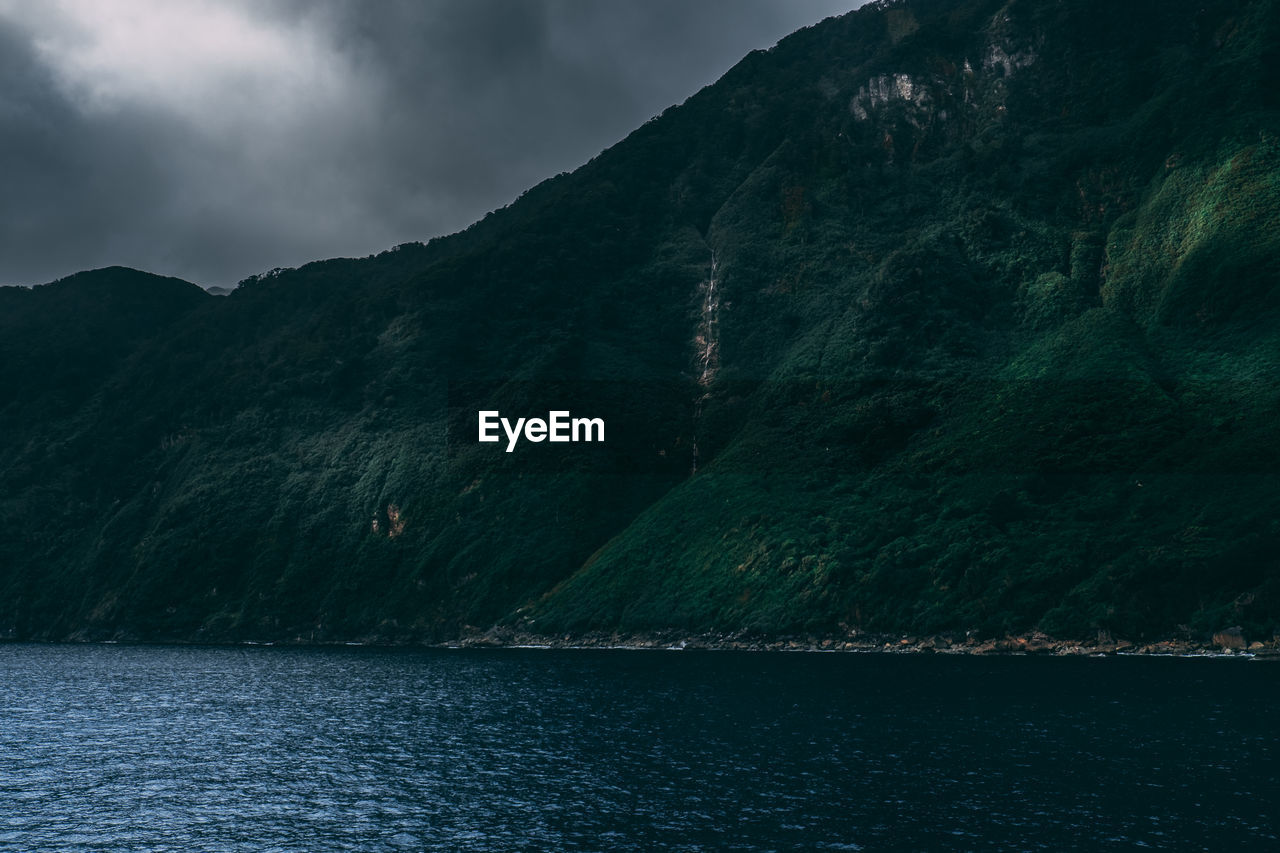 Scenic view of sea by mountains against sky